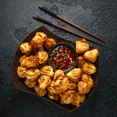 Chinese takeaway finger food Vegetable wontons with sweet chilli dip sauce and chop sticks.の写真素材