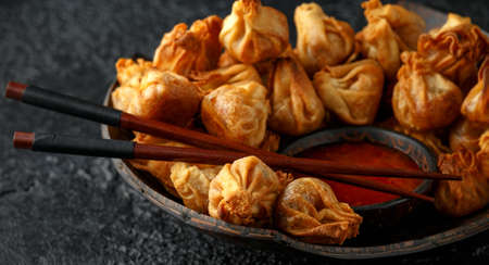 Chinese finger food wontons with sweet chilli dip sauce and chopsticks