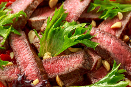 Beef Steak with Romesco sauce, nuts and vegetables on white plate.