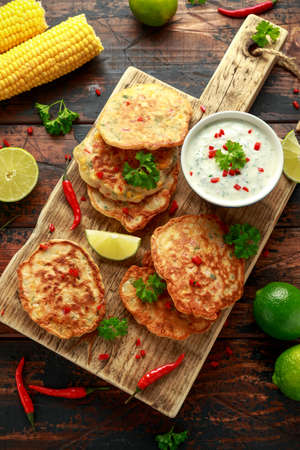 Corn fritters, pancake with dip white sauce, lime and chilli on wooden board