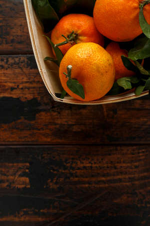 Mandarins Tangerines with green leaves on wooden table.