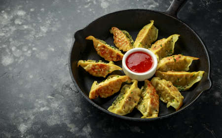 Fried yaki Gyoza served on cast iron skillet, pan with sweet chilli sauce and sesame seedsの写真素材