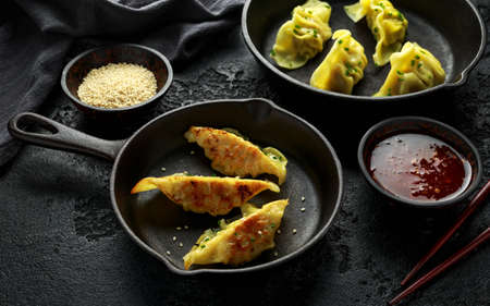 Steamed and Fried yaki Gyoza served on cast iron skillet, pan with sweet chilli sauce and sesame seedsの写真素材