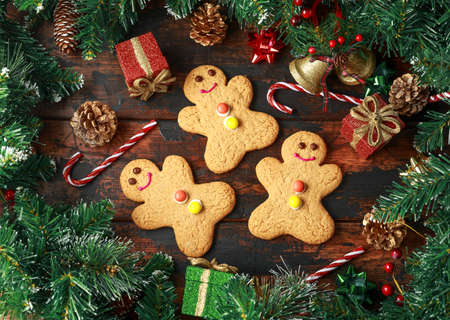 Christmas Gingerbread Men with decoration, gifts, green tree branch on wooden rustic table