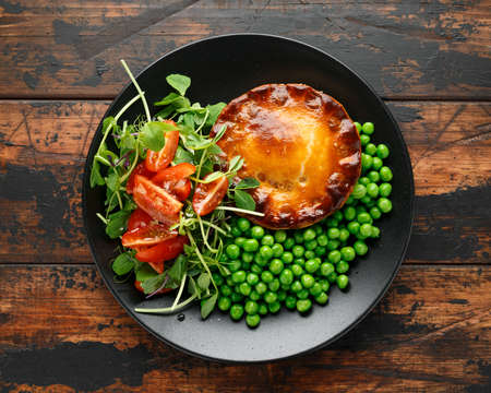 Beef steak pies with rich onion gravy served with sweet peas and saladの写真素材