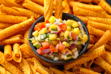 cheddar cheese tortilla rolls, chips in serving basket with mango salsaの写真素材