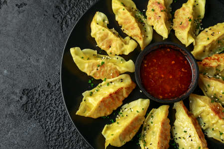 Fried yaki Gyoza served on stone plate with sweet chilli sauce and sesame seedsの写真素材