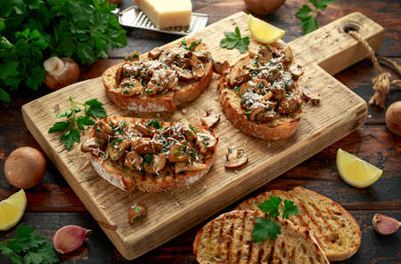 Grilled mushroom toast with parsley, lemon and parmesan cheese on wooden board. healthy vegan food