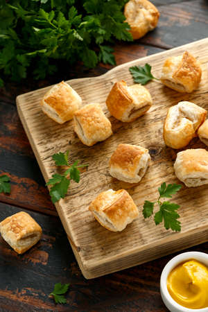 Pork sausage rolls with mustard and ketchup sauce on wooden board