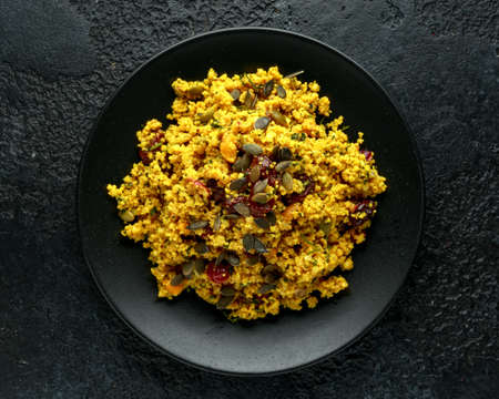 Morrocan style fruit couscous salad with raisins, dried apricots and pumpkin seeds on dark backgroundの写真素材