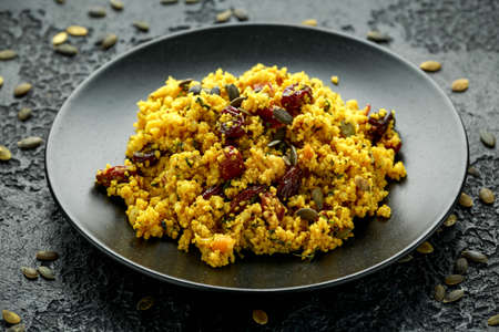 Morrocan style fruit couscous salad with raisins, dried apricots and pumpkin seeds on dark backgroundの写真素材