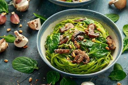 Vegan garlic mushroom pasta with spinach and avocado pesto drizzled with sesame seeds and roasted pine nutsの写真素材