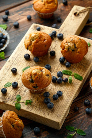 Blueberries muffins, cupcake with mint and berry on wooden board.の写真素材