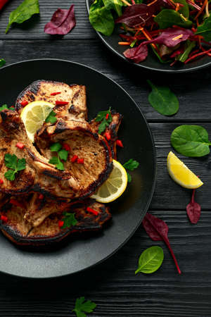 Homemade Grilled Pork loin chops in lemon sauce with herbs on rustic wooden table.の写真素材