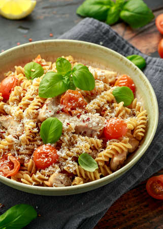 Healthy Chicken, fusilli pasta with tomatoes, basil and parmesan cheese. on wooden table.の写真素材
