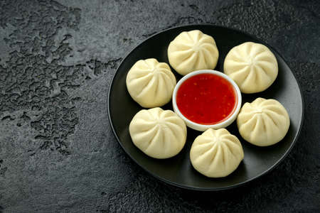 Steamed Buns with duck stuffing, chili sauce on black plate.の写真素材