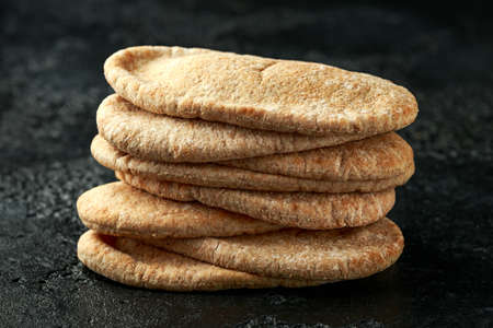 Pita bread on black stone plate on rustic background