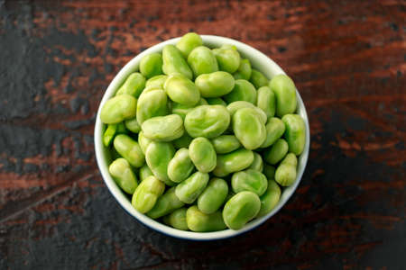 Green Broad Beans in a blue bowl on wooden table. healthy food.の写真素材