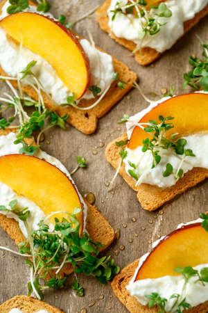 Cottage cheese and nectarine wedges on melba toast appetizers drizzled with runny honey and served with cress salad microgreen. Healthy party finger foodの写真素材
