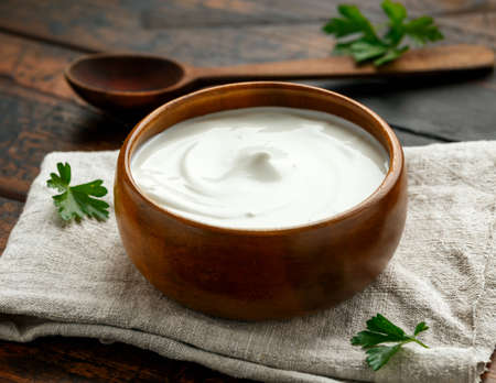 Greek yogurt in bowl on rustic wooden table.の写真素材