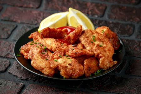 Fried Battered Chicken breast fillets served with lemon wedges.の写真素材