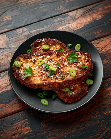 Parmesan cheese French Toast with spring onion on black plateの写真素材