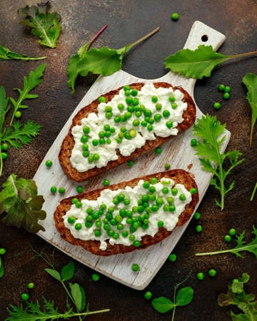 Vegetarian seeded sourdough bread open sandwich with cottage cheese and petit poit peas sprinkled...
