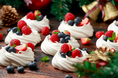 Meringue nests mini pavlova cakes with fresh berries strawberry blueberry raspberry and mint for dinner desert with Christmas festive decorationsの写真素材