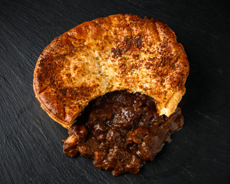 British beef steak pie with onion, wine gravy on rustic stone board