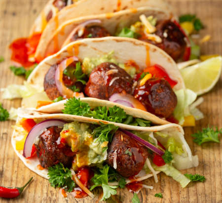 Meat free beetroot and pea protein meatballs taco wraps with avocado guacamole, sweet chilli sauce and lime wedgesの写真素材