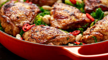 One-pot braised chicken thighs with kale and cannellini beans served with chili peppersの写真素材
