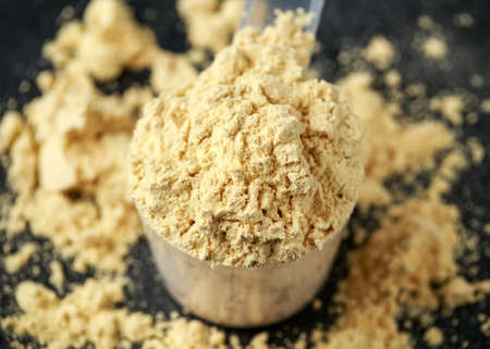 Scoop of Pea Vegan protein powder on dark rustic background. Sport nutrition.