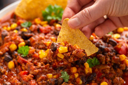 Chilli con Carne with tortilla chips and cheese in white bowl. Mexican food.の写真素材