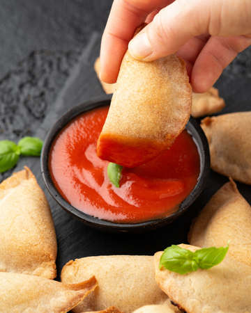 Margarita Margherita pizza parcels pockets filled with tomato, mozzarella cheese and basil served on black slate board with marinara sauce and olives. Party finger foodの写真素材