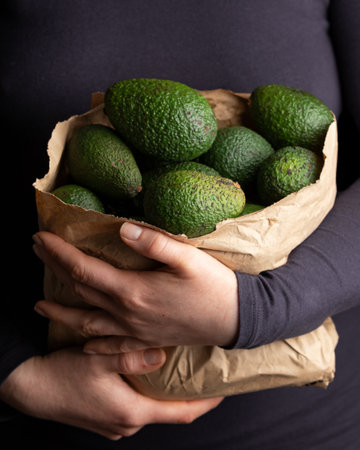 Woman holding paper carrier bags, full of fresh avocado. Healthy food.の写真素材