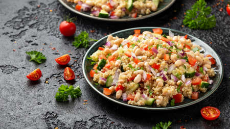 Quinoa white bean salad with cherry tomatoes, cucumber, red onion and herbs. Healthy vegan foodの写真素材