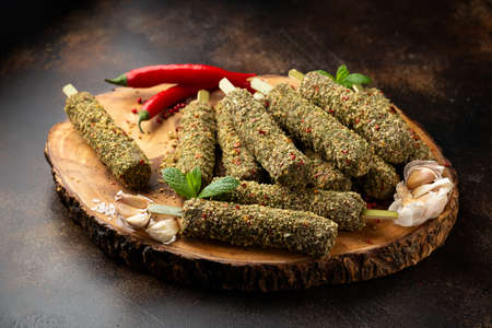 Raw lamb Kofta kebabs on skewers with mix of herbs on wooden board. Ready to cookの写真素材