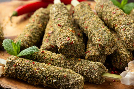 Raw lamb Kofta kebabs on skewers with mix of herbs on wooden board. Ready to cookの写真素材