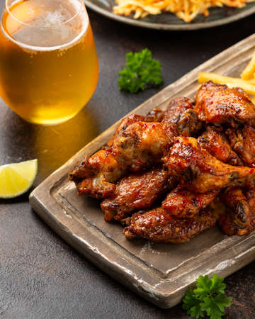 Buffalo chicken wings with beer, french fries on wooden board. fast foodの写真素材