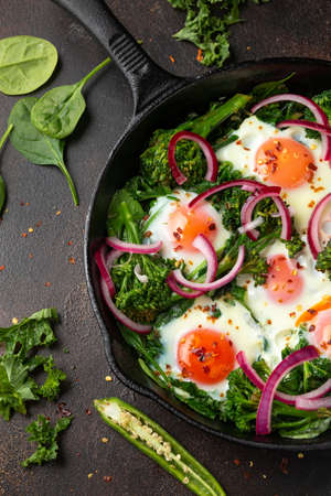 Green shakshuka with golden yolk eggs, kale, spinach and tender broccoli served with pickled onions and chilli flakesの写真素材
