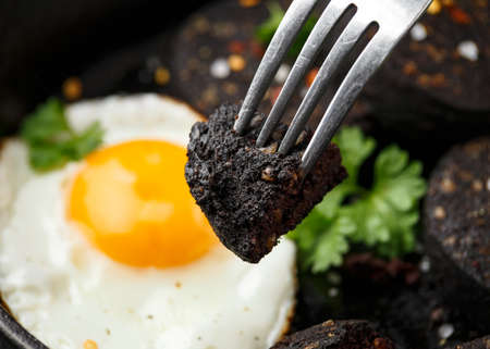 Cooked Black Pudding with egg, herbs and parsley on iron cast panの写真素材