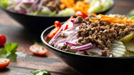 Cheeseburger, hamburger or burger keto salad with beef, fresh tomatoes, red onion, pickled gherkins,...