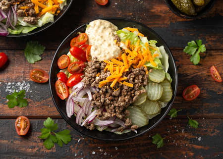Cheeseburger, hamburger or burger keto salad with beef, fresh tomatoes, red onion, pickled gherkins, lettuce and home made sauce dressingの写真素材