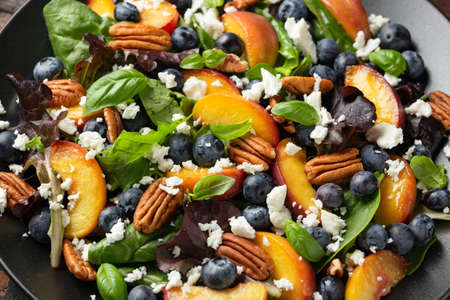 Peach, blueberry salad with vegetables, feta cheese and pecan nuts. Healthy summer foodの写真素材