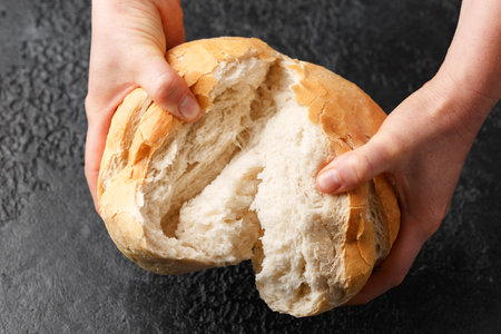 Woman hands breaking freshly baked cob bread