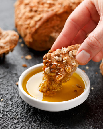 Woman dipping bread into bowl of tasty olive oil