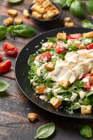 A delicious chicken caesar salad with parmesan cheese, tomatoes, croutons and dressingの写真素材