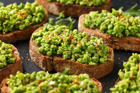 Mashed peas sourdough bread toast with sea salt flakes and chilli served on black slateの写真素材