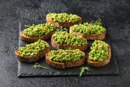 Mashed peas sourdough bread toast with sea salt flakes and chilli served on black slateの写真素材