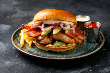 Chicken sandwich, burger with bacon, pickled onion, avocado, mayonnaise and french friesの写真素材